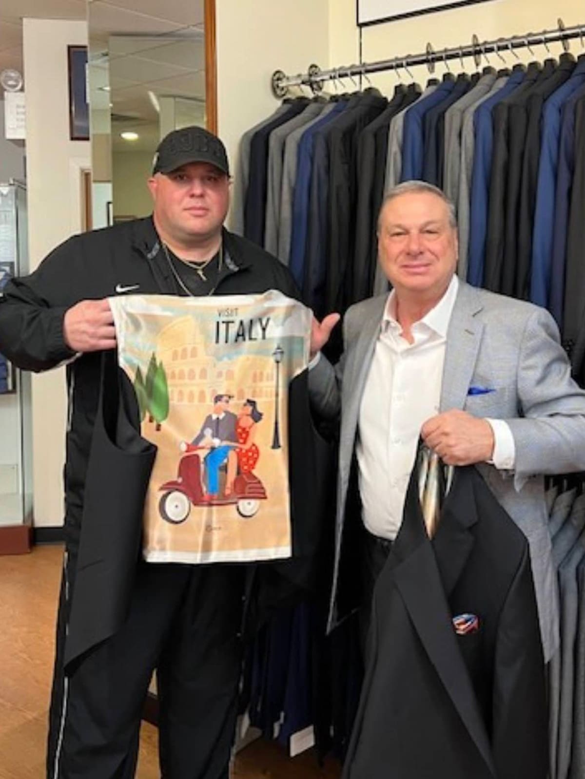 Big Dom and a member of the Ventresca Ltd. team holding up a custom jacket with an Italy-themed printed lining