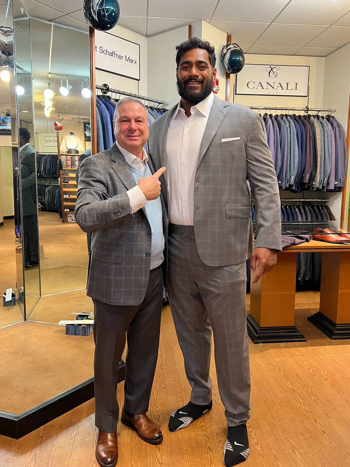 Jordan Mailata in a grey suit with a member of the Ventresca Ltd. team, inside the store