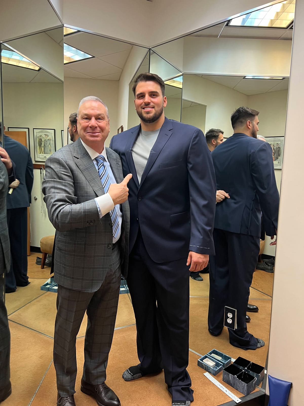 Jon Runyan Jr. in a navy suit with a member of the Ventresca Ltd. team, in the store's fitting area